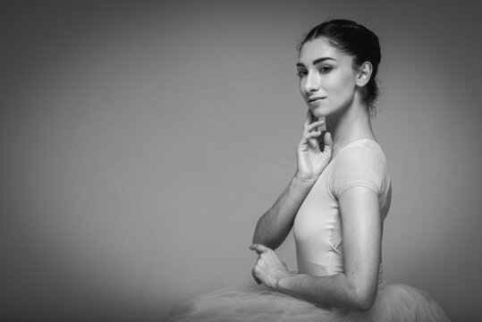 classic black and white photo, young pretty, fragile, beautiful ballerina dancing in a long pale pink dress with tulle on a uniform background, restrained tone. Ballet, dancing, dancer selective focus