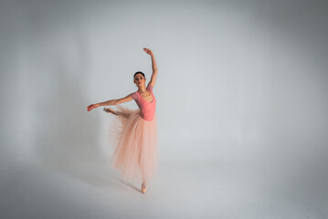 young pretty, fragile, beautiful ballerina dancing in a long pale pink dress with a tulle on a uniform background, low key. Ballet, dancing, dancer	