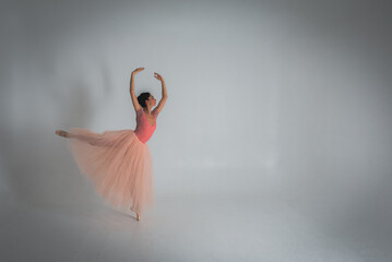 young pretty, fragile, beautiful ballerina dancing in a long pale pink dress with a tulle on a uniform background, low key. Ballet, dancing, dancer	