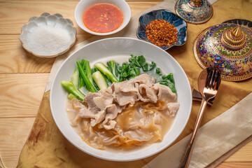 Wide Rice Noodles with pork and kale in Gravy Sauce  Served with condiments, chili powder , chili sauce and sugar. Asian food.