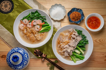 Shrimp Wide Rice Noodles and Pork Wide Rice Noodles with  kale in Gravy Sauce  Served with condiments, chili powder , chili sauce and sugar. Asian food.
