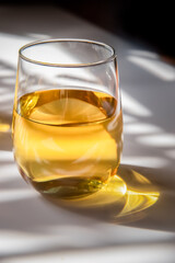 glass of white wine or apple juice, cider on white background with harsh shadows, natural light, bright golden drink. High quality photo