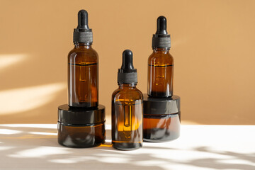 Mock-ups of unmarked cream jars and vials with dropper lids with face serum made of amber glass....