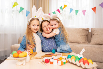 Obraz na płótnie Canvas a happy mother and sweet little daughters with rabbit ears celebrate Easter.