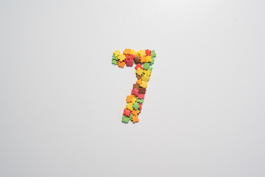 Numeral Seven From Sweet Pastry Topping In The Form Of Colorful Foliage On A White Background.