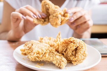 closeup dish of chicken fried with blur background of woman hand eating unhealthy food
