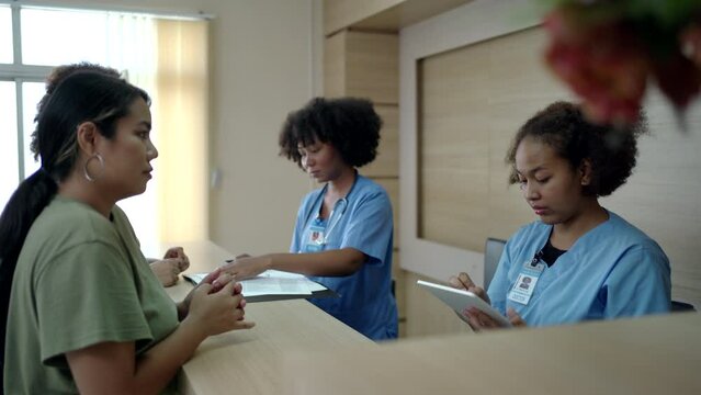 Patient talking to doctor at hospital desk and signing a document.