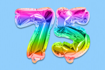 Obraz na płótnie Canvas Rainbow foil balloon number, digit seventy five on a blue background. Birthday greeting card with inscription 75. Anniversary concept. Numerical digit. Celebration event, template.