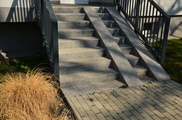 ramp combined with a gray concrete staircase and a handrail specially adapted for wheelchairs....