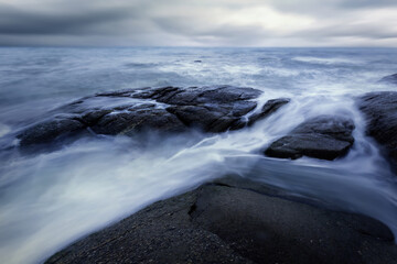 Beautiful long exposure shot of seascape at sunrise,silky smooth sea wave sweeping past the rock.