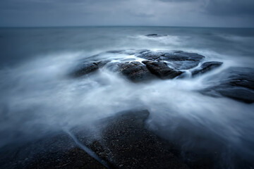 Beautiful long exposure shot of seascape at sunrise,silky smooth sea wave sweeping past the rock.