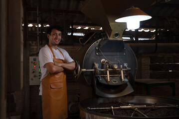 Private business owner controlling coffee roasting process. Coffee roaster working on roasting equipment.