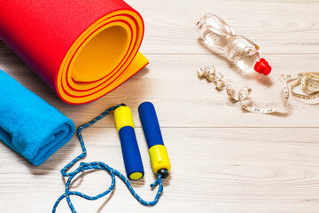 Yoga mat and different tools for fitness on floor in room.