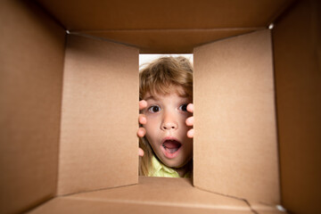 Kid opening package. Child boy age 6 year opening a carton box and looking inside, unpacking...