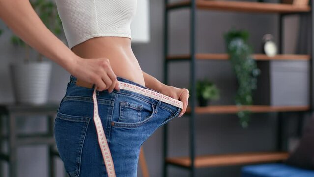 Closeup slim woman waist in big jeans measurement weight loss progress belly beauty shape