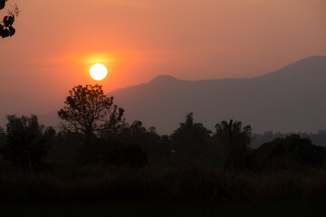 Sunset landscape orange sky silhouette mountain and trees.