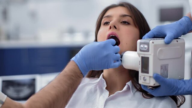 Female patient with open mouth doctor assistant shooting x ray of dental cavity at clinic