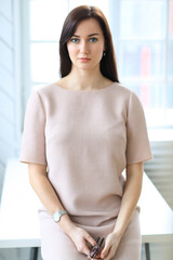 Stylish attractive young businesswoman with a lovely smile standing in the office grinning at the camera