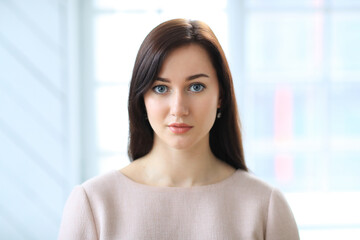 Fototapeta premium Stylish attractive young businesswoman with a lovely smile standing in the office grinning at the camera