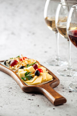 Glasses of white and red wine and cheese appetizer board