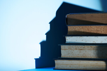 stack of books with shadow against blue background