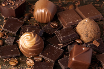 Chocolate pieces and candy on dark wooden table.
