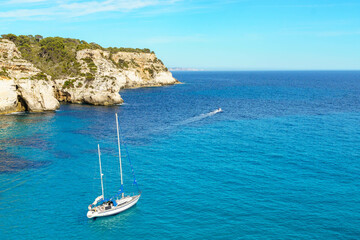 Turquoise waters of Cala Macarelleta with a small boat, in Menorca