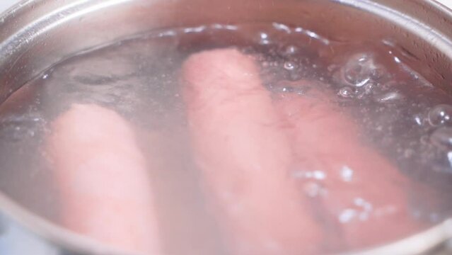 Appetizing sausages are boiled in water close-up. Boiling