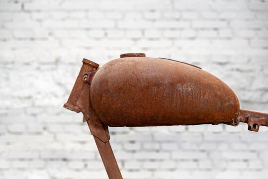 Close up of an coroded fuel tank of jawa motorcycle. White brick wall in the background.