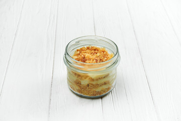 Sponge cake with cream in a jar on a white wooden background