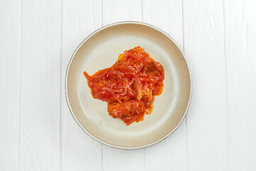 Fish stew in red sauce with vegetables on a white wooden background