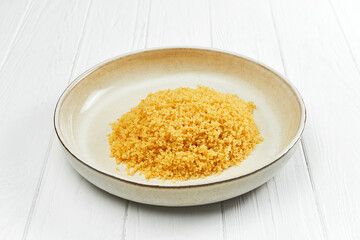 Bulgur garnish in a plate on a white wooden background