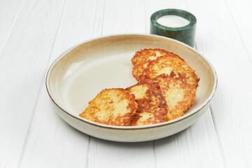 Ukrainian potato draniki or hash browns in a plate on a white wooden background