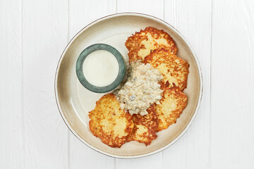Ukrainian potato draniki or hash browns in a plate on a white wooden background