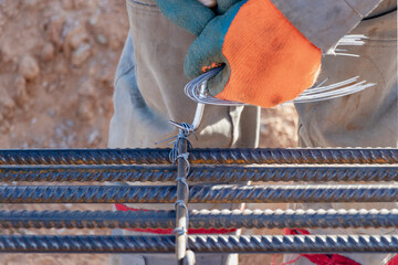 A worker uses steel tying wire to fasten steel rods to reinforcement bars. Close-up. Reinforced...