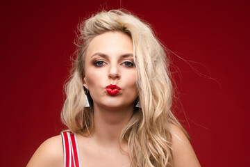 Fototapeta premium Beautiful blonde in a red swimsuit with bright makeup and red lips