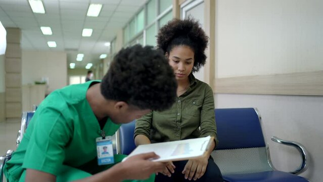 Doctor comes to talk to the woman patient who waiting at the hospital ward.