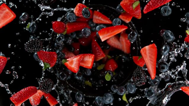 Super slow motion shot of rotating exploded berries fruit with splashing water on black at 1000fps.