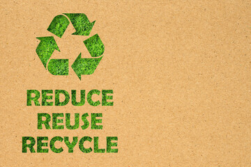 Kraft paper hole of Reuse, Reduce, Recycle symbol and text on green grass background. Environmental...