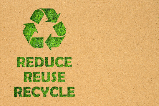 Kraft paper hole of Reuse, Reduce, Recycle symbol and text on green grass background. Environmental conservation concept.