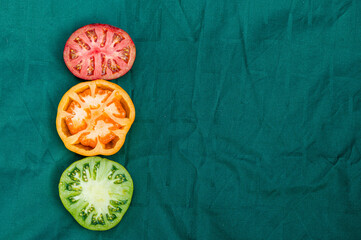 red, yellow and green tomato halves on a green background, closeup from above, abstract semaphore