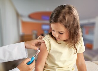 Female nurse giving an arm injection to a child. Little kid in getting a shot at a modern...