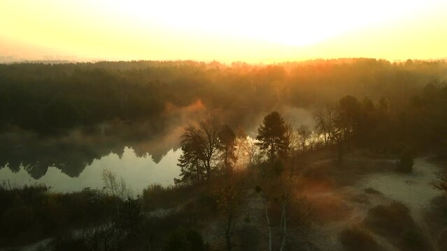 Drone flight over the water surface and the shore of the lake. Foggy morning