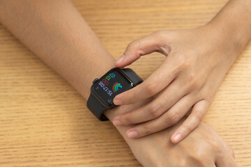 Female hands touching on a smart watch on wooden desk , top view.