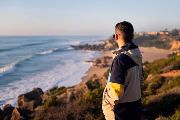 rear view of a man with jacket looking at the sea