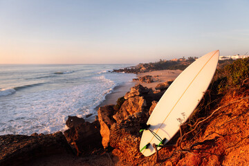surfboard on the rocks by the beach at sunset
