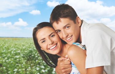 Obraz premium Happy couple holding hands and walking through wheat field while looking away. Nature landscape.