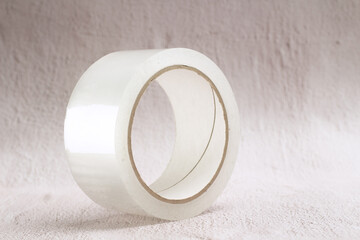 thick wide roll of transparent adhesive tape on a light rustic background