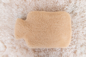 Colorful hot water bag standing on animal skin. There is an animal hide cover on the hot water bags.