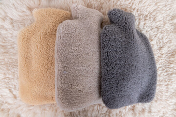 Colorful hot water bag standing on animal skin. There is an animal hide cover on the hot water bags.